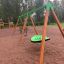 Vihreä Swing Seat GBNS keinussa leikkikentällä metsän reunalla.