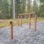 Ulkoleikkikentän Over-under-puurakenteiset kiipeilytelineet metsässä sorapohjaisella alueella.