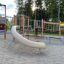 Moderni El Dorado leikkikenttä, jossa on kiipeilytelineet ja kaareva liukumäki metsäympäristössä.