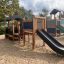Leikkijuna, jossa torni ja liukumäki, leikkikentällä hiekalla.