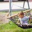 Lapsi istuu Double Hammock (Metal) -riippumatossa ulkona.