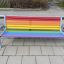 Colourful bench leikkipuiston sateenkaarivärinen penkki metallisilla käsinojilla.
