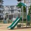 Vantage point with a slide - vihreä ja beige leikkiteline liukumäellä modernissa kaupunkipihaympäris