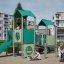 Tower playhouse with a slide - vihreä leikkiteline liukumäellä kerrostalojen pihalla.