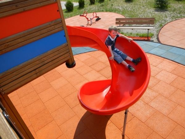 Poika leikkipuistossa liukumäessä Rubber Tiles 90 -turvalaatoilla.