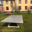 Betoninen pöytätennispöytä ulkona nurmikolla talojen edessä.