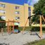 Leikkikenttä kiipeilytelineen ja renkaalla varustetun keinun kanssa.
