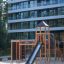 Odin natur leikkipuiston puurakenteinen liukumäki ja kiipeilyteline hiekkaisella alustalla.